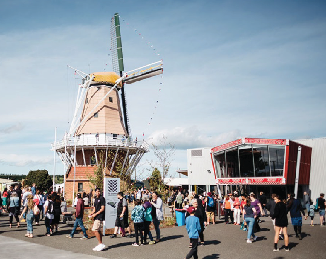 Outside of Te Awahou Nieuwe Stroom with a crow of people walking around.